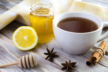 Tea, honey, cinnamon and lemon on the wooden background 
