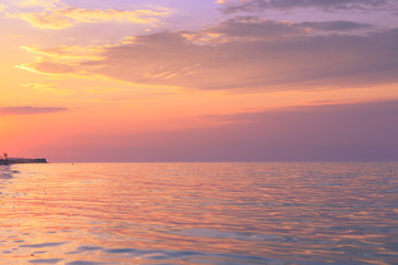 Fototapeta premium Radiance at sunset by the sea on the coast with warm color overflows and a beautiful sky