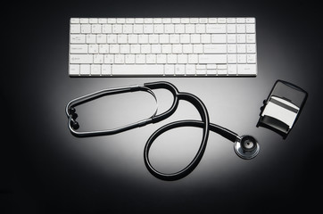 Stethoscope isolated on black background. Sterile doctors office desk. Medical accessories on black reflective table background with copy space around products. Photo taken from above.