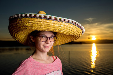 young woman with sombrero on the beach at sunset