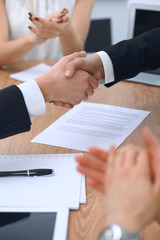 Close up of business people shaking hands at meeting or negotiation in the office. Partners are satisfied because signing contract