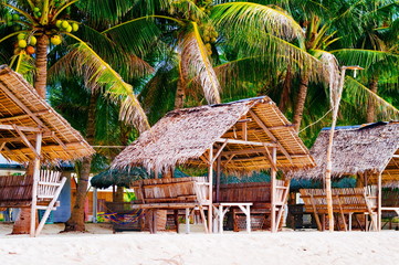 Fototapeta premium Summer sunshades and bamboo armchair on the tropical white sand beach,