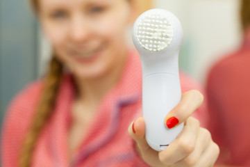 Woman holding facial cleansing brush