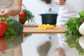 Close-up of four human hands are cooking in a kitchen. Friends having fun while preparing fresh salad. Vegetarian, healthy meal and friendship concept