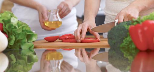 Close-up of four human hands are cooking in a kitchen. Friends having fun while preparing fresh...