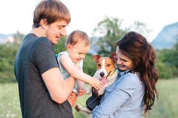 Close-up portrait of happy family with pet - jack russel terrier, walking outside. Baby and dog.