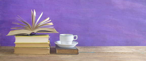 open book and cup of coffee on purple background,free copy space