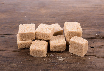 Brown cane sugar cubes on wooden background. top view