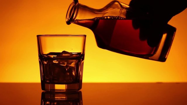 Glass filled with whiskey to a bottle