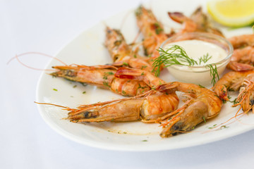 Shrimps in white plate with sauce and lemon at restaurant