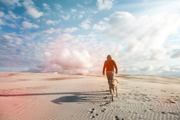 Mann mit Weimaraner Jagdhund auf Wanderung über eine Sanddüne