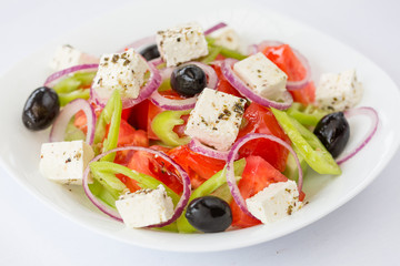 Traditional Greek salad in white plate in taverna