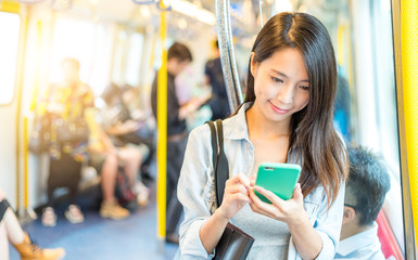 Woman working on mobile phone inside train compartment