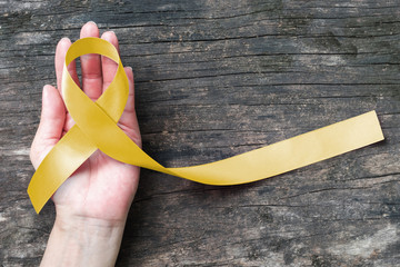 Sarcoma Bone cancer awareness with yellow ribbon symbolic color on helping hand (isolated with...