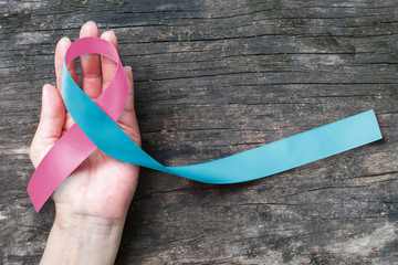 Pink blue ribbon awareness (isolated with clipping path) on helping hand for SID Birth defect illness to end obstetric fistula  - obrazy, fototapety, plakaty