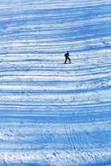 Girl skiing on the late afternoon snowy slopes with transversal shadows