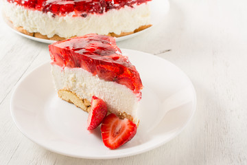 Delicious homemade cake with strawberries on white wooden table.