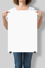 Woman holding a blank A2 poster mockup isolated on a gray background.