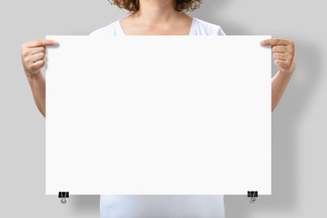 Woman holding a blank A2 poster mockup isolated on a gray background. - obrazy, fototapety, plakaty