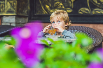 Obraz na płótnie Canvas Cute little boy drinking tea in cafeteria