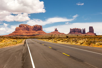 Fototapeta na wymiar Road passing through Monument Valley, beautiful sunny day with blue sky in summer, Utah, USA