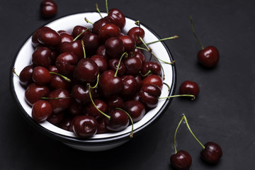 Cherry in plate on a black background.
