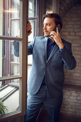 Businessman talking on cell phone in office near window