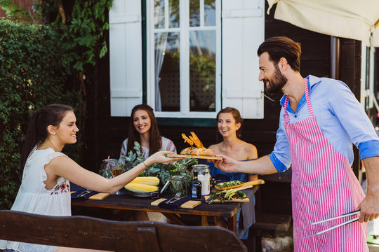 Grillmeister Mann serviert gegrilltes an den Damentisch