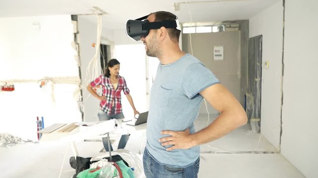 Couple with vr goggle and laptop watching virtual project at their new home
