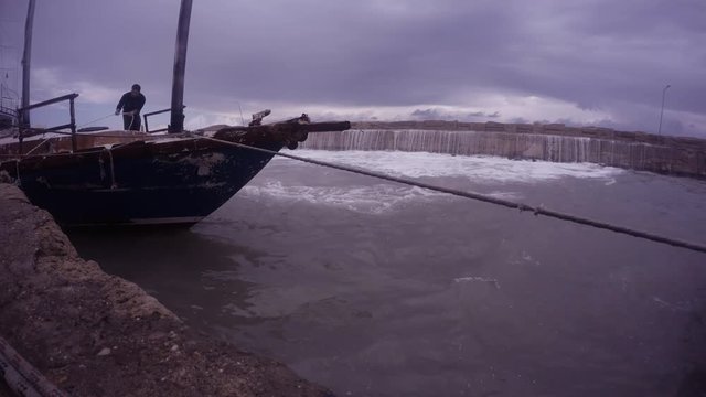 Seaman Binds Ship to Mooring on Background Ancient Pier Covers With Big Wave in Centre of Girne (Kyrenia)