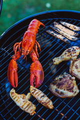 Lobster and chicken on grill cooking grate with asparagus
