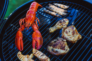 Lobster and chicken on grill cooking grate with asparagus