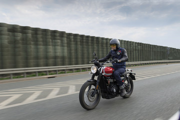 Man in blue jeans, grey helmet riding fast red motorcycle