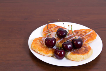 Curd fritters with cherries
Syrniki - cheese pancakes, curd fritters - traditional Russian and Ukrainian snack, on white plate, served with cherries and cream