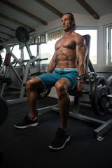 Obraz na płótnie Canvas Muscular Man Exercising Trapezius On Machine