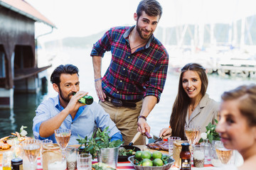 Man serving pan for friends at sea barbecue party