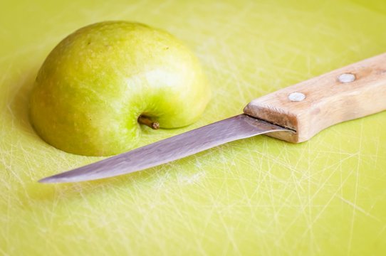 Green apple cut in slices on a cutting board with a steel knife with wooden handle illustrative. Apple has a content of numerous minerals and vitamins. It is one of the world's healthiest foods.