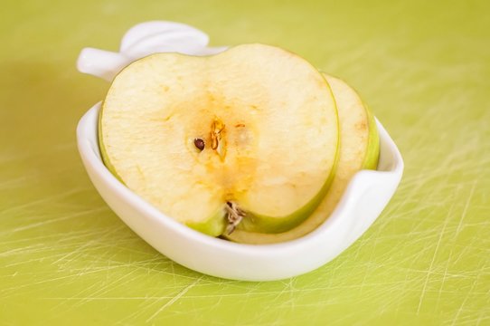 Two thin green apple slices on a porcelain plate turned brown after staying outside in the fresh air close up stock image.