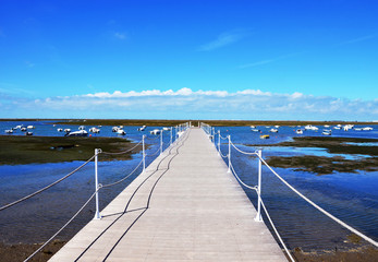 Fototapeta premium Wooden Harbour Jetty at Ria Formosa with blue sky in background in Faro Marina, Algarve, Portugal