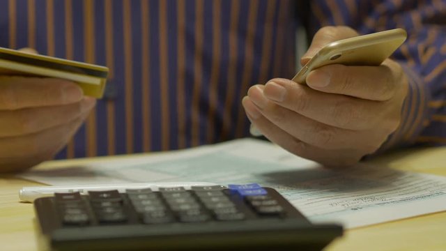 Elderly Man Text Messaging On Smartphone And Tax Form 1040, Credit Card