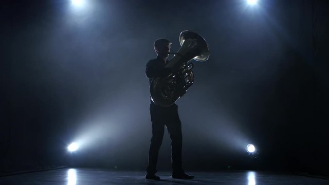 Instrumentalist plays on wind instrument classical melody. Studio in smoke