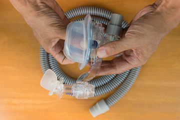 CPAP mask assembly.After routine cleaning cpap mask , man hands assembling all parts include of elbow kit,cushion,forehead pad and blue clip,flat lay.