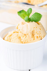 Homemade ice cream with salted caramel in a bowl on a white wooden background, soft focus, vertical