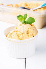 Homemade ice cream with salted caramel in a bowl on a white wooden background, soft focus, vertical
