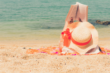 Beautiful asian bikini woman sitting on beach reading a book novel