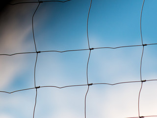 Close-up of metal wire fence with sky in background