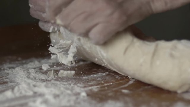 Senior woman hands knead dough on a table in her home kitchen. Slow motion