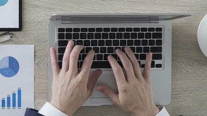 Male opening laptop and starting typing, conducting data analysis, office desk - Powered by Adobe