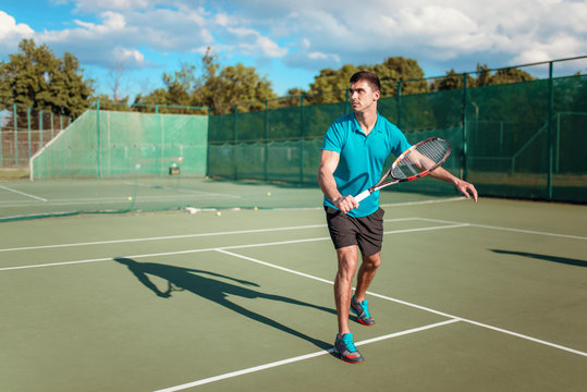 Athletic male tennis player plays on outdoor court
