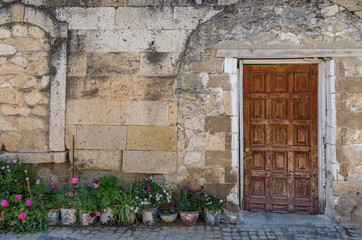 Fototapeta na wymiar Old house facade with old wooden door and flower pots